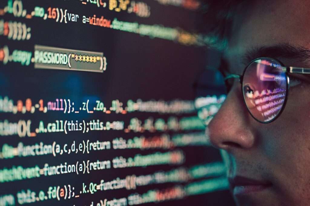 SEO Hannover - Eine Nahaufnahme einer Person mit Brille, die tief auf einen Computerbildschirm starrt, auf dem bunte Codezeilen angezeigt werden. Dieser für das Webdesign in Hannover wichtige Abschnitt enthält Code zu Passwörtern. Die Reflexion des leuchtenden Bildschirms schimmert auf den Gläsern. Local SEO Agentur Hannover.