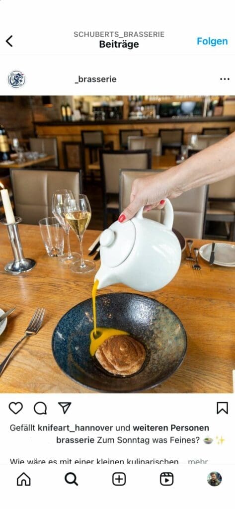 Webdesign Hannover - In einem gemütlichen Restaurant-Ambiente, das an ein Instagram-würdiges Meisterwerk der Food-Fotografie erinnert, gießt eine Person elegant leuchtend orangefarbene Suppe aus einem weißen Krug in eine Schüssel, die mit dunkelbraunem Brot serviert wird. Der Tisch ist tadellos mit Weingläsern und glänzendem Besteck gedeckt, bereit, in einem perfekten Screenshot festgehalten zu werden. Local SEO Agentur Hannover.