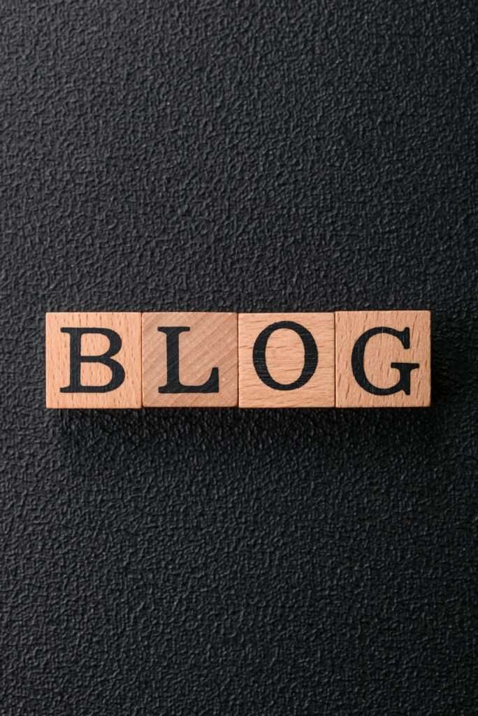SEO Hannover - Holzklötze bilden das Wort „BLOG“ vor einem strukturierten schwarzen Hintergrund. Local SEO Agentur Hannover.