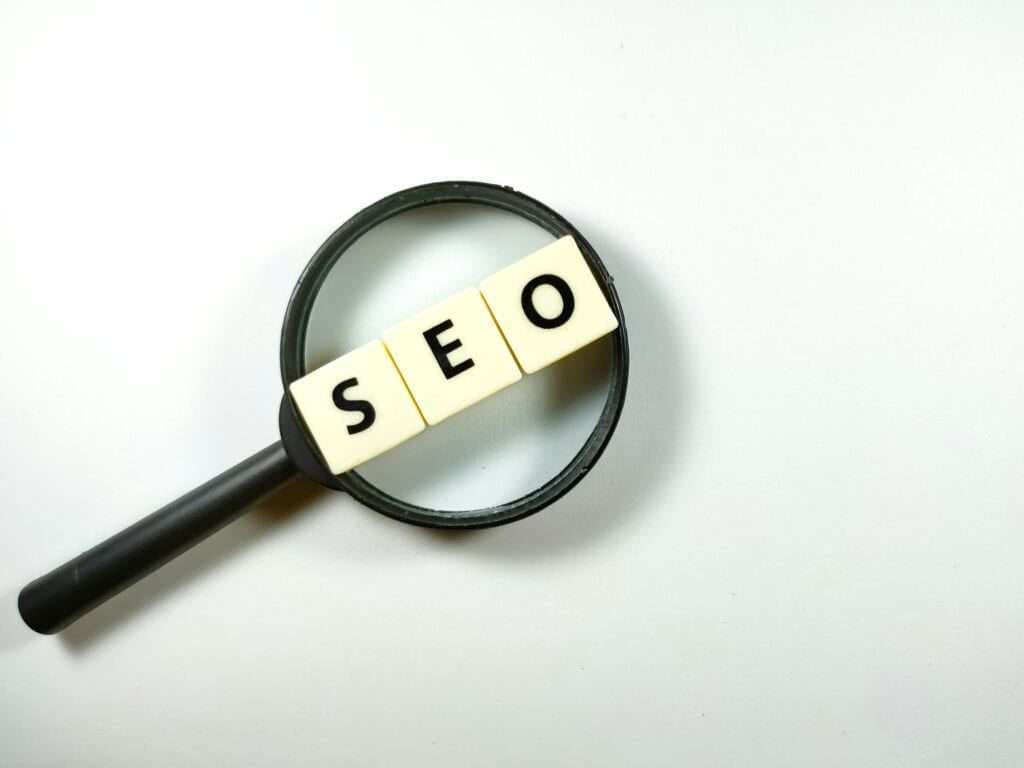 Magnifying glass and scrabble letters with text SEO search engine optimization on white background