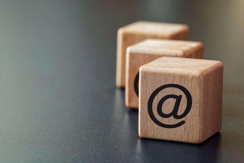 Webdesign Hannover - Drei Holzklötze sind in einer Reihe auf einer dunklen Oberfläche platziert und ähneln den Schritten für die Website-Navigation. Jeder Block ist mit dem Symbol „@“ versehen, was ihm eine digitale Note verleiht. Die Blöcke sind leicht unscharf positioniert und treten in den Hintergrund. Local SEO Agentur Hannover.