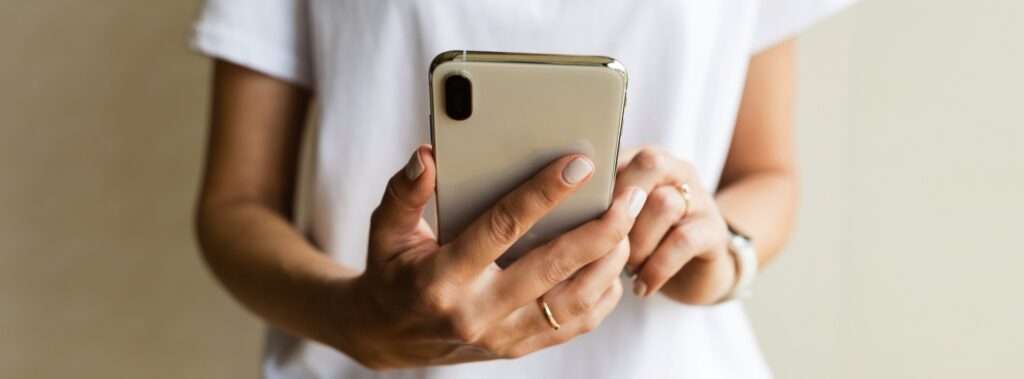 Webdesign Hannover - Eine Person im weißen Hemd hält ein Smartphone in der Hand und prüft möglicherweise die neuesten Updates zu einem neu gestalteten Website-Design. Das Telefon mit Ring und Uhr ist in einer Schutzhülle verstaut und fällt vor dem schlichten Hintergrund auf. Local SEO Agentur Hannover.