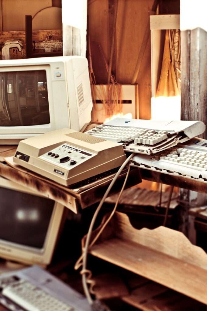Webdesign Hannover - Eine Sammlung von Vintage-Computern und -Tastaturen, die wahllos aufgestapelt sind, erinnert an ein vergangenes digitales Zeitalter, ist aber reif für einen Website-Relaunch. Die Anordnung umfasst CRT-Monitore und einen beigen Computer, alle mit Abnutzungs- und Altersspuren, vor einem rustikalen Holzhintergrund. Local SEO Agentur Hannover.