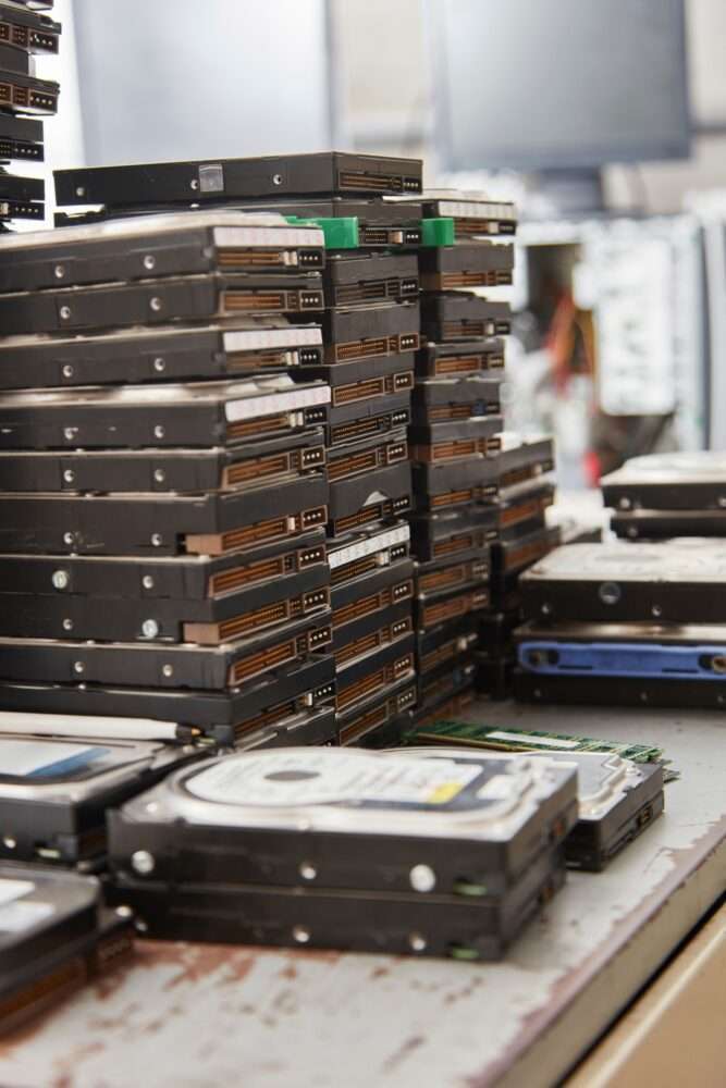 Webdesign Hannover - In einer Werkstatt stapeln sich Festplatten auf einer Werkbank, im Hintergrund sind verschiedene Computerkomponenten zu sehen. Während sie auf Recycling oder Wiederaufarbeitung warten, spiegelt ihre Organisation die Sorgfalt wider, die für die effektive Verwaltung eines WordPress-Wartungsvertrags erforderlich ist. Local SEO Agentur Hannover.