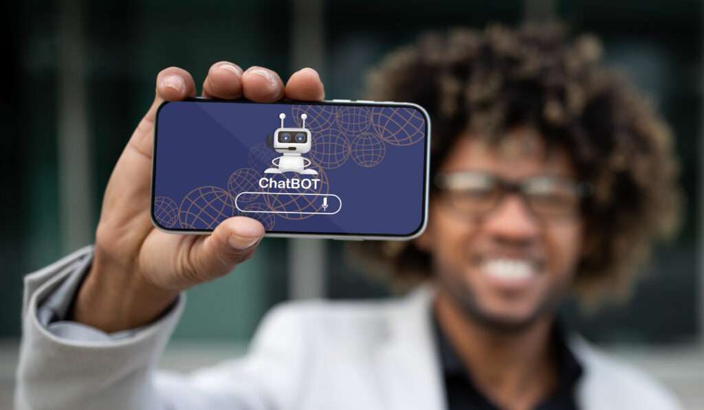 Webdesign Hannover - Eine Person mit lockigem Haar und Brille hält ein Smartphone mit einer Chatbot-Oberfläche. Auf dem Bildschirm sind ein Robotersymbol und der Text „ChatBOT“ zu sehen, was auf Fragen wie „Wie implementiere ich einen Chatbot?“ hindeutet. Der Hintergrund ist unscharf, um den Fokus auf das Telefon zu lenken. Local SEO Agentur Hannover.